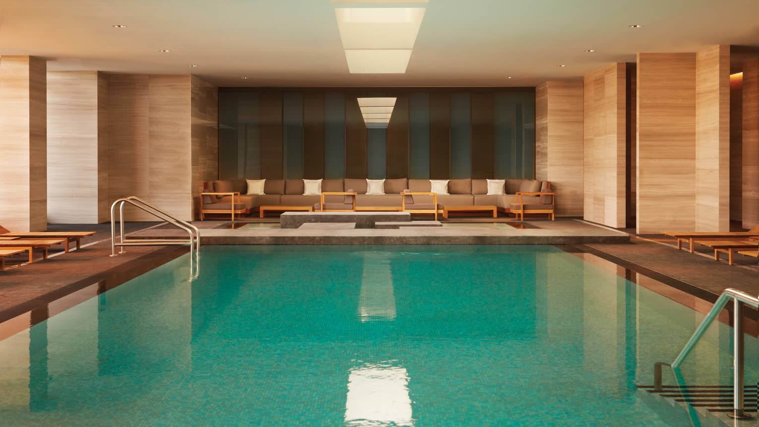 Long plush patio sofas at end of large indoor swimming pool