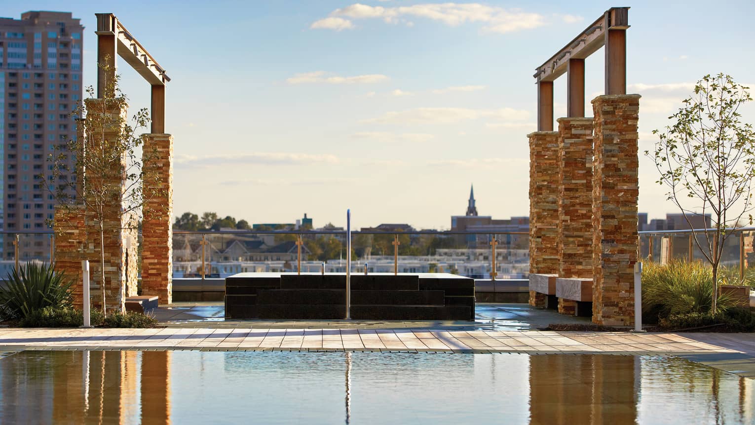 Tall brick pillars, frames over outdoor rooftop whirlpool and reflecting pool