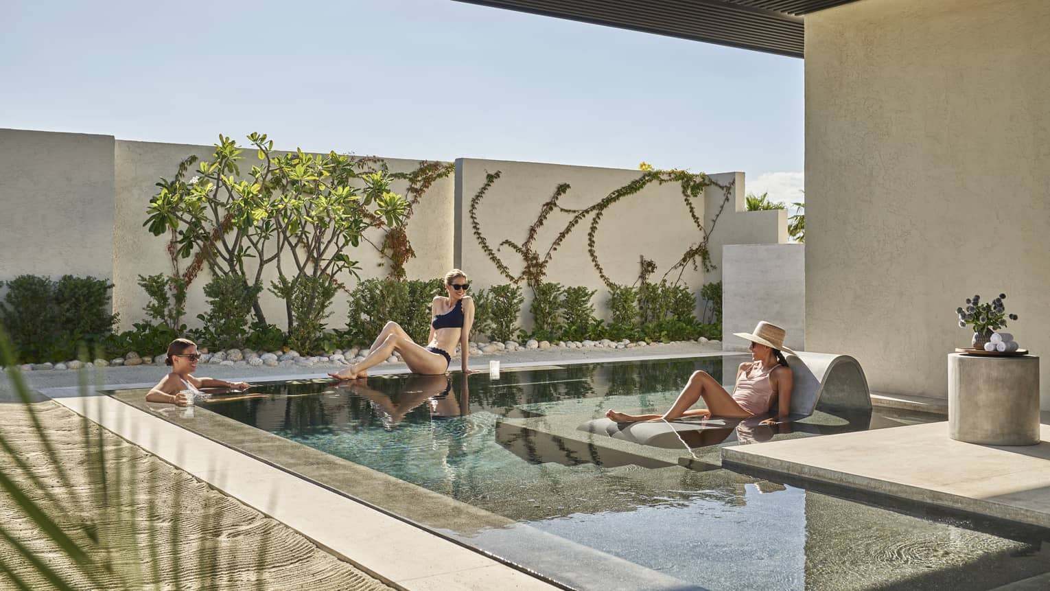 Three women lounging around a small outdoor pool.