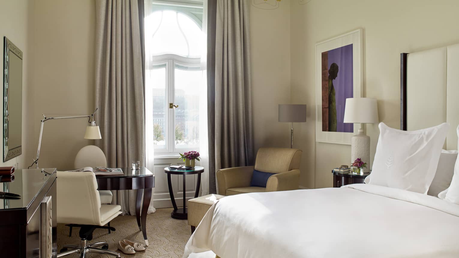 Danube River-View Room bed with white linens, cream-coloured desk chair and armchair, tall picture window, curtains