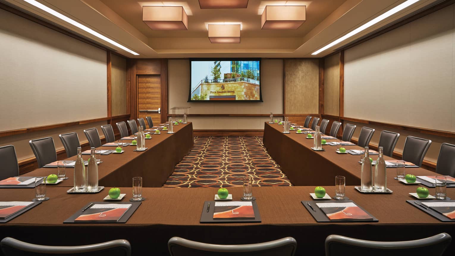 Magenta large ballroom lined with modular meeting tables, chairs facing screen