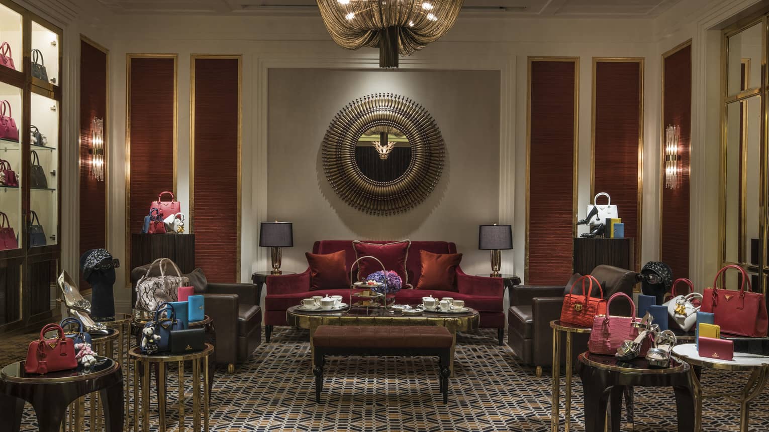 Salon with red velvet sofa, small tables with designer handbags 