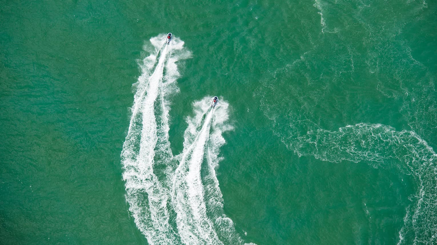 Aerial view of two jet skis, trails on water in ocean