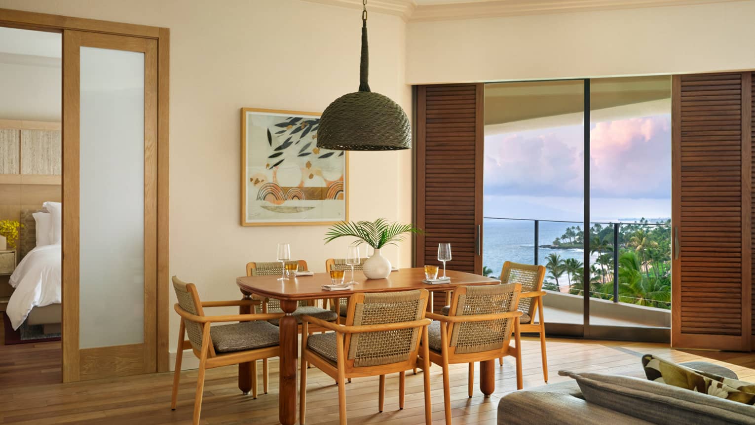 Dining room in an ocean-view resort room, featuring table set for six, and an entryway into a bedroom