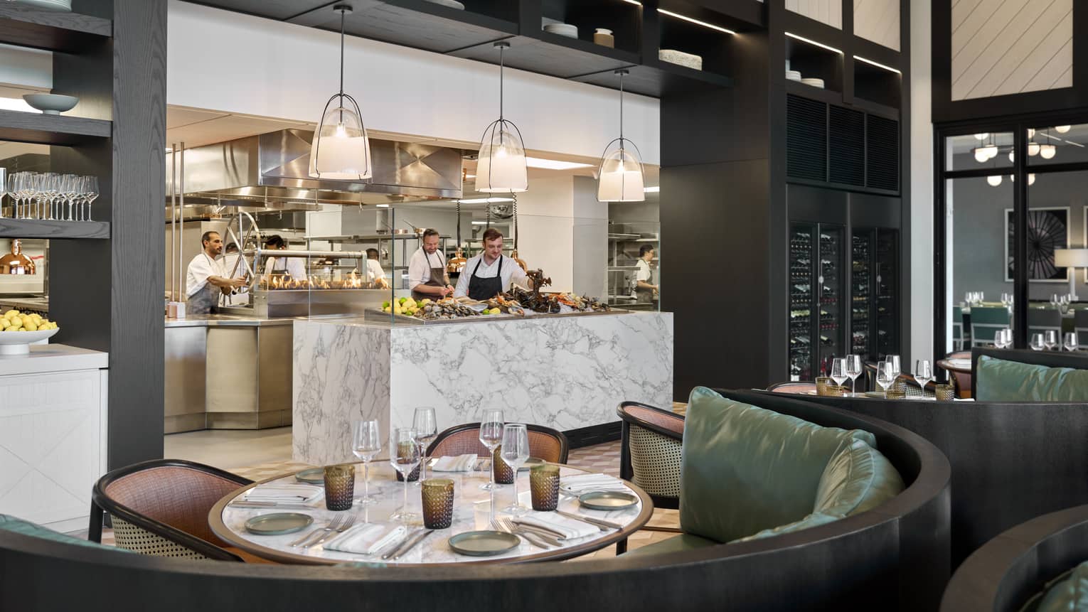 Restaurant table with curved booth, facing the chefs counter and kitchen
