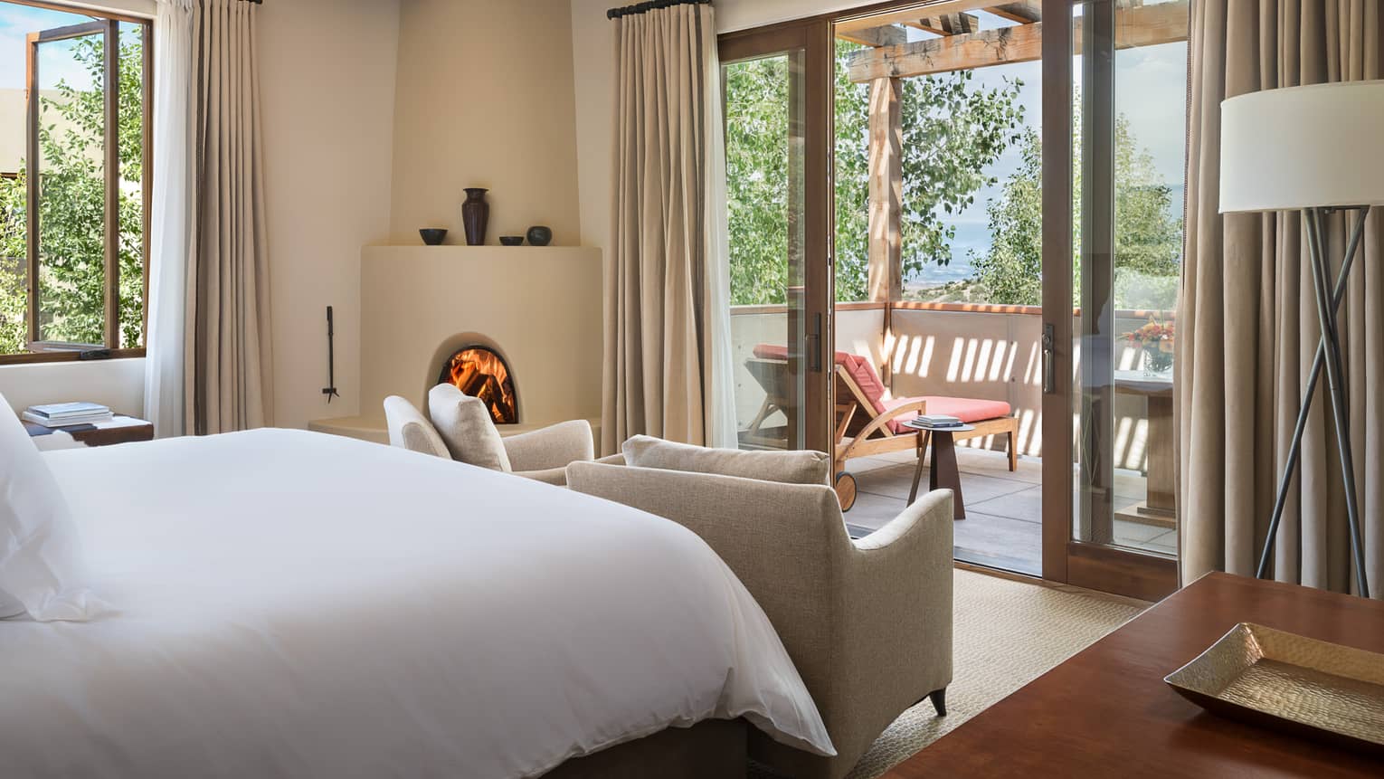 Mountain-View Casita bed, curved white fireplace, chairs by balcony doors