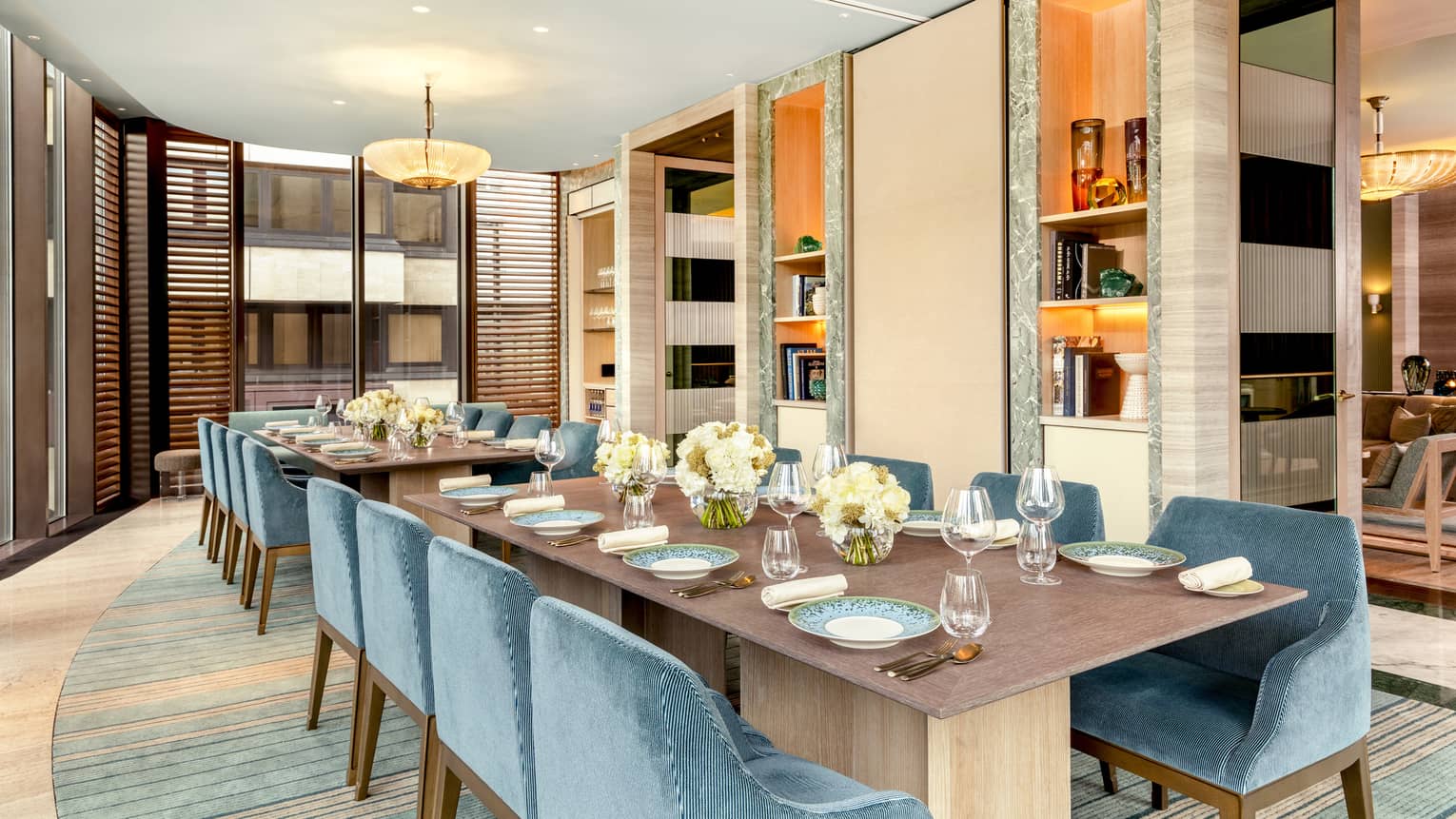 Long dining table flanked by blue velvet chairs in brightly lit private dining room