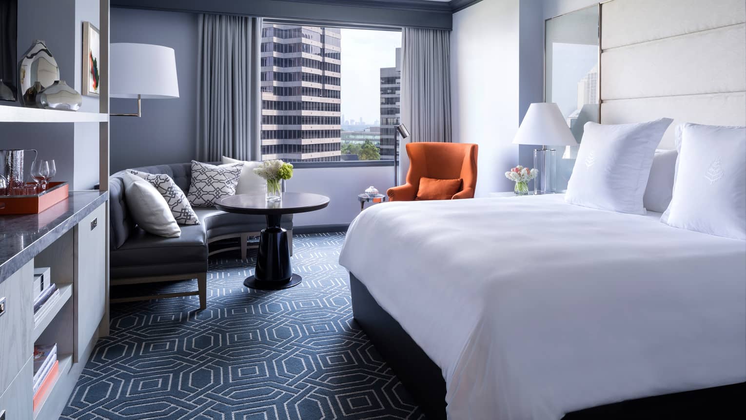 Midtown Deluxe Room bed, blue carpet, marble bar, curved corner sofa, orange accent chair
