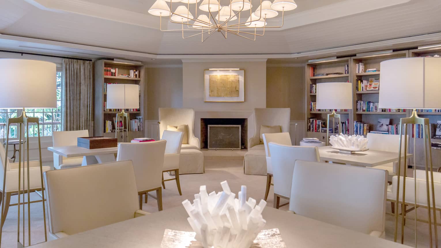 A brightly lit library with many tables and chairs and bookshelves lining the walls.