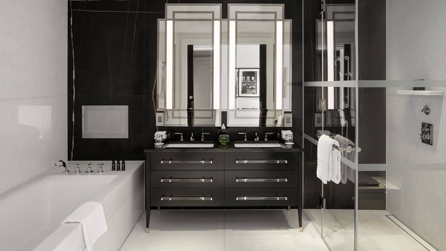 A bathroom with glass shower, tub, double sink and large mirror.