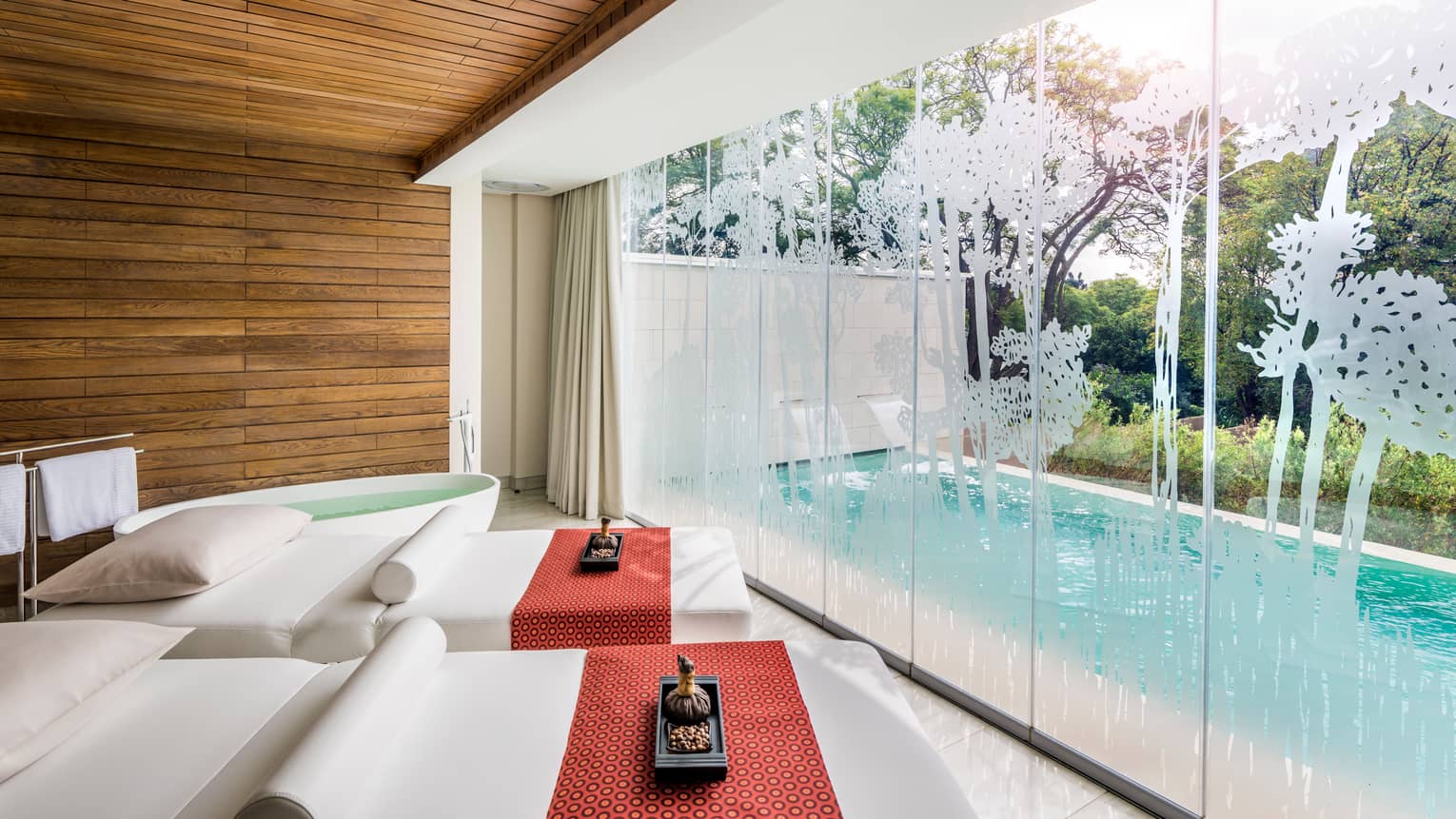 Couples massage tables with trays with oil, salts in front of sunny Spa window