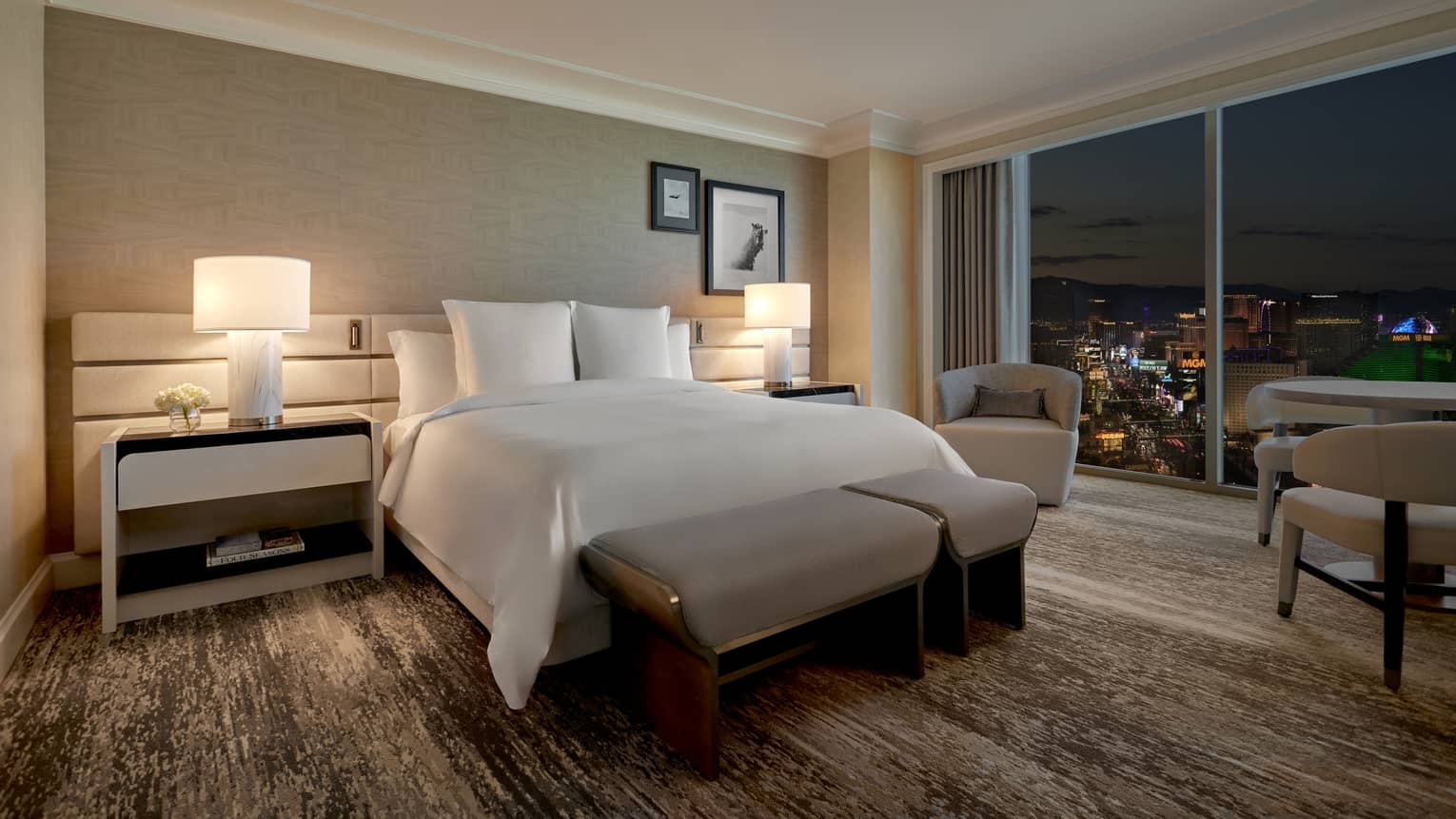 A dimly lit room with bed, large window and two side tables.