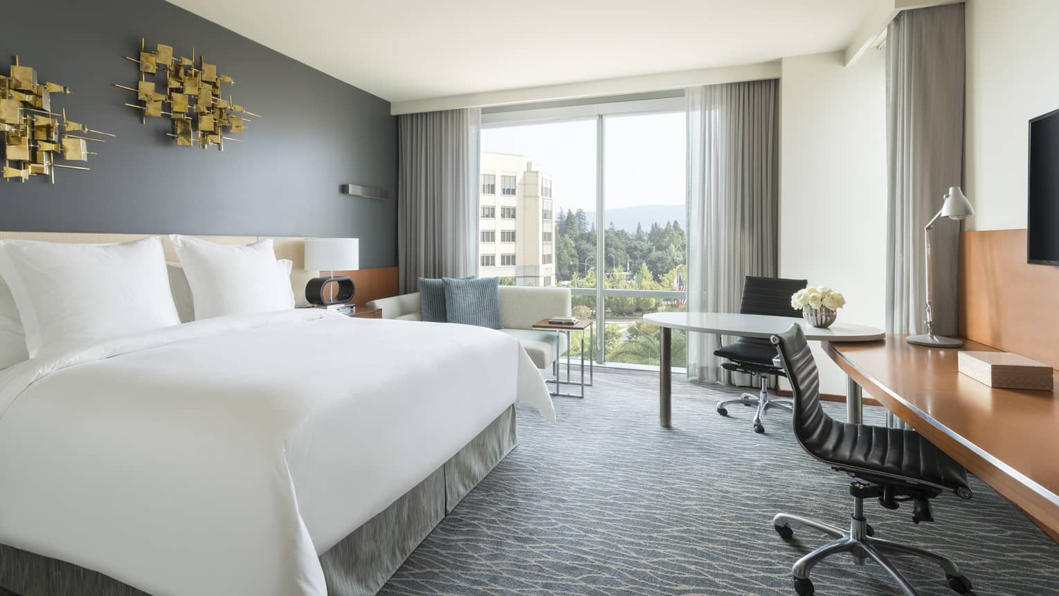 Premier Room bed under modern gold art, two desks, chaise by floor-to-ceiling window