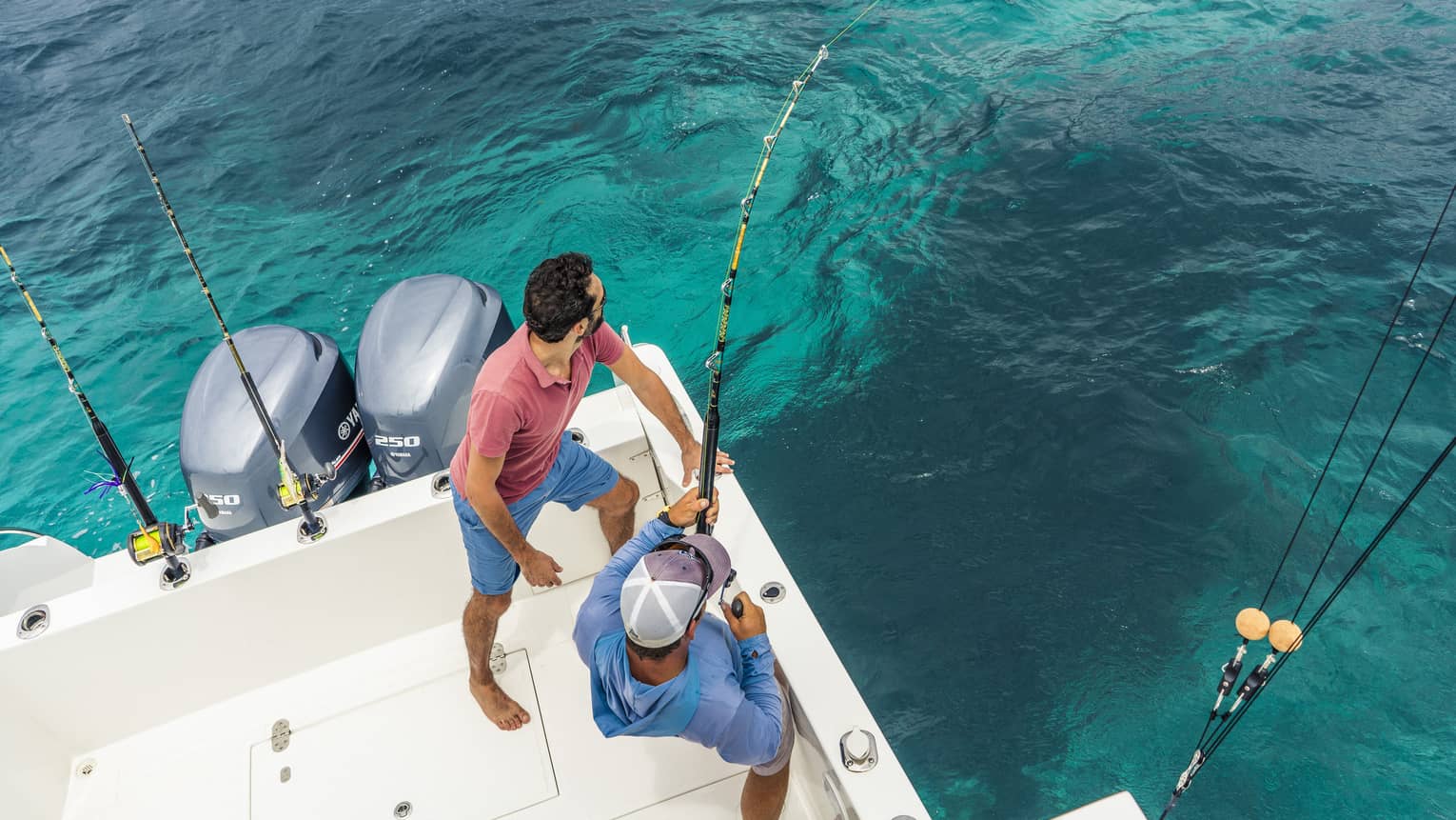 Aerial view of two men fishing off white boat with fishing rods