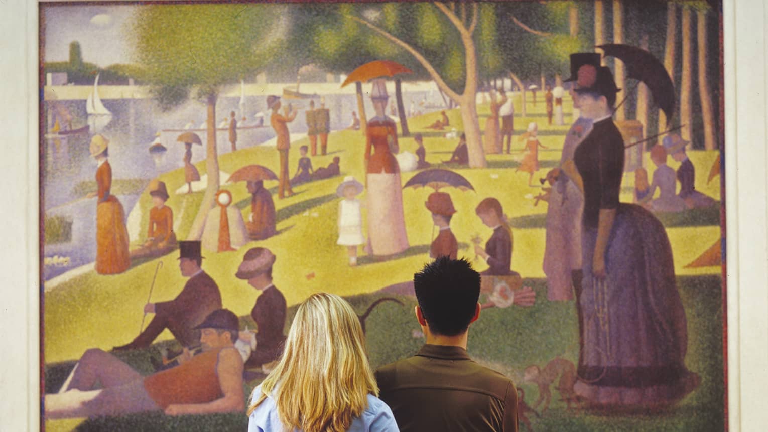 A couple admiring Seurat's iconic Pointillist painting, A Sunday on La Grande Jatte, depicting people strolling in a park.