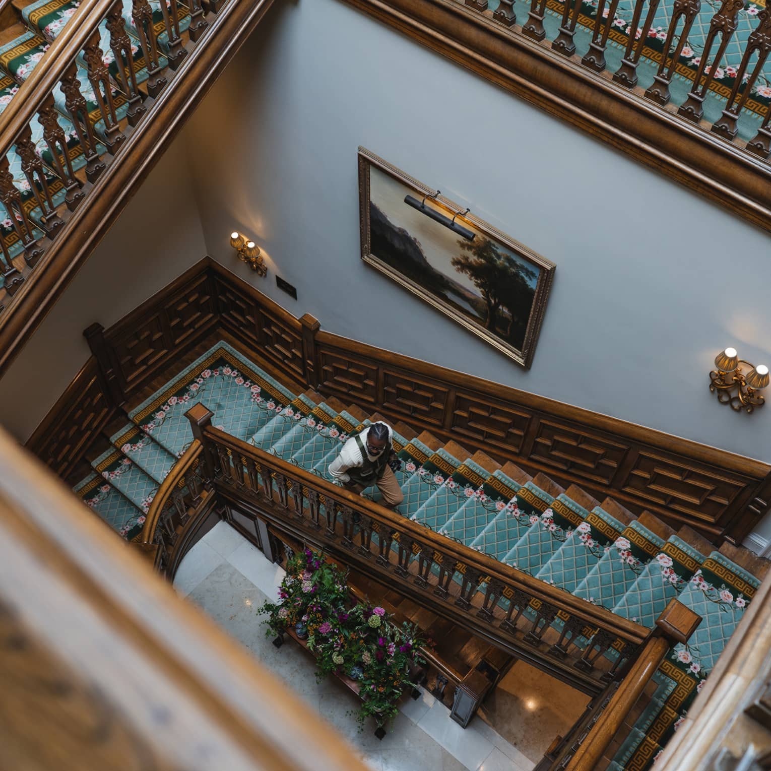 A rectangular wood spiral staircase with a teal blue runner