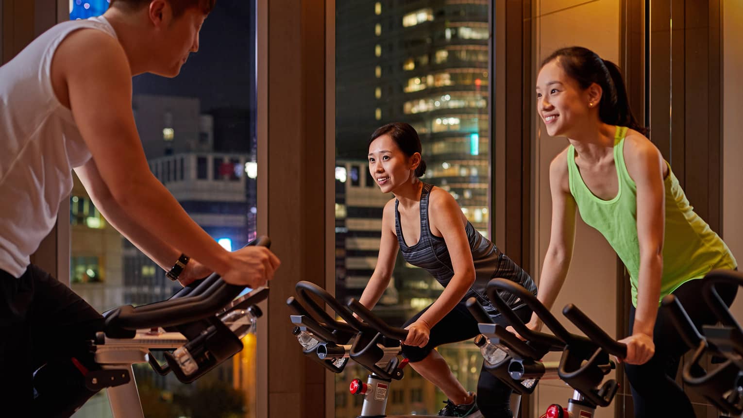 Man and two women on bikes in private spin class 