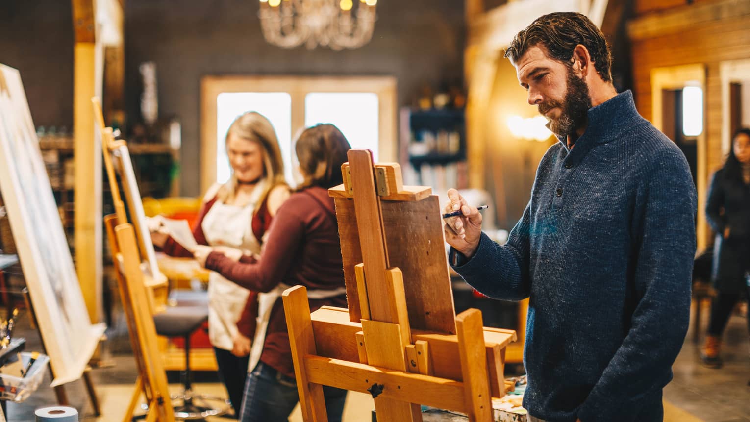 A man uses an easel and paints during a class