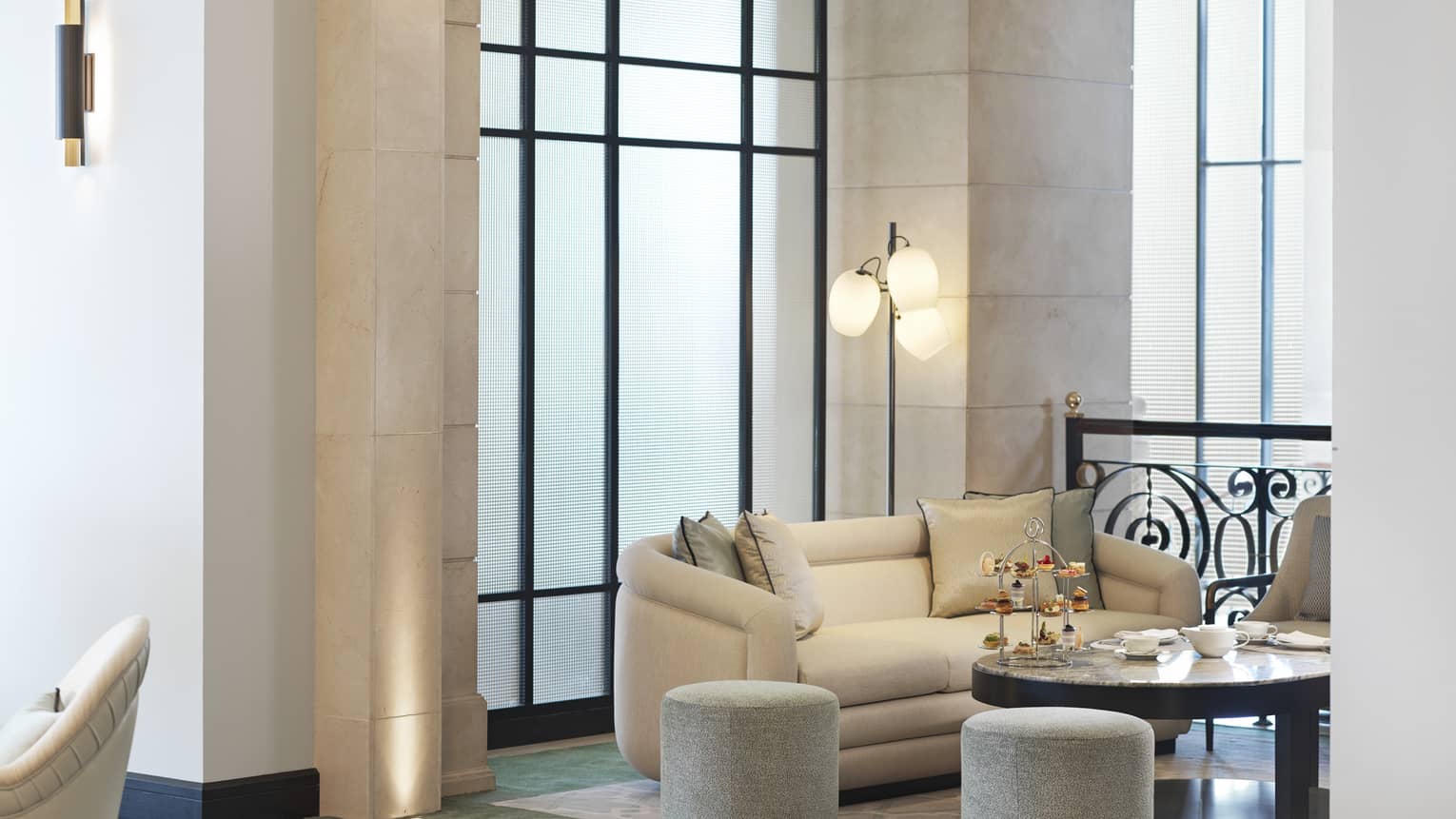 A cream love seat facing a large circular table in a marble seating area. 