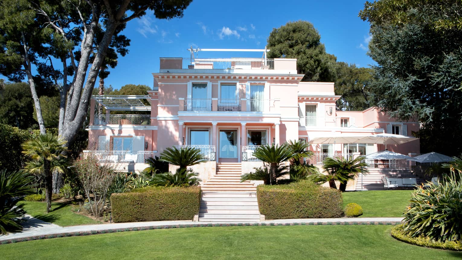 Manicured gardens, steps up to large three-storey pink Villa Rose-Pierre