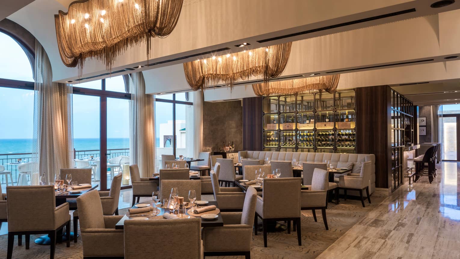 Dining area with water views and wall of wine bottles behind couch