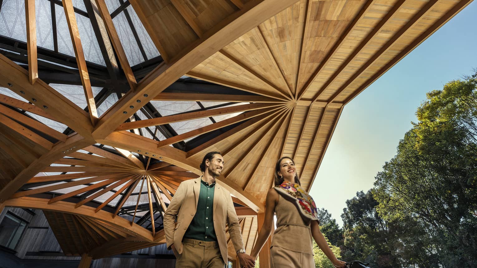 Couple walks hand-in-hand under the elaborate wooden awning of the Hotel