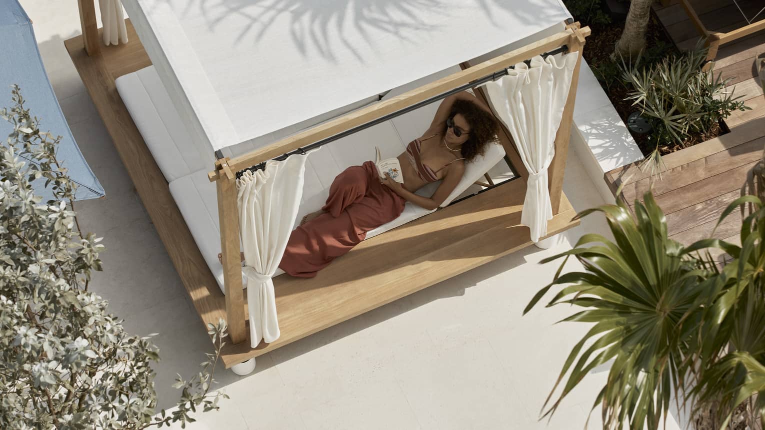 Aerial view of woman lounging in a covered poolside daybed