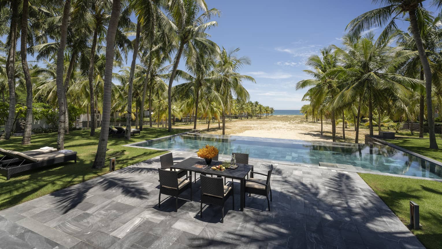 Three-Bedroom Pool Villa pool area with dining table, lounge chairs, palm trees, ocean views