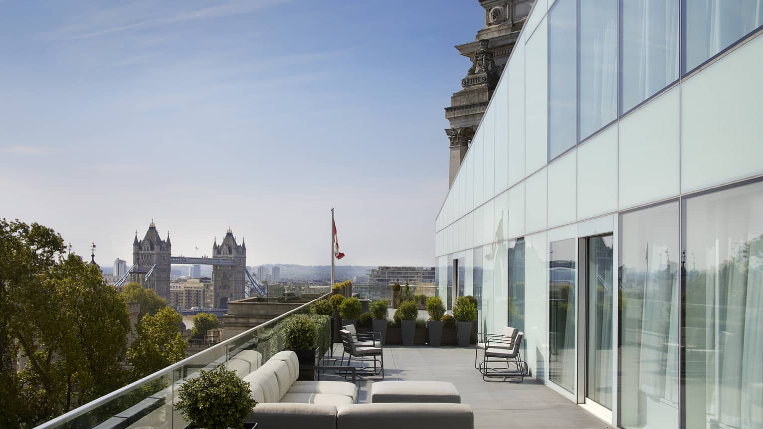 Patio with white sofas under modern two-storey glass wall