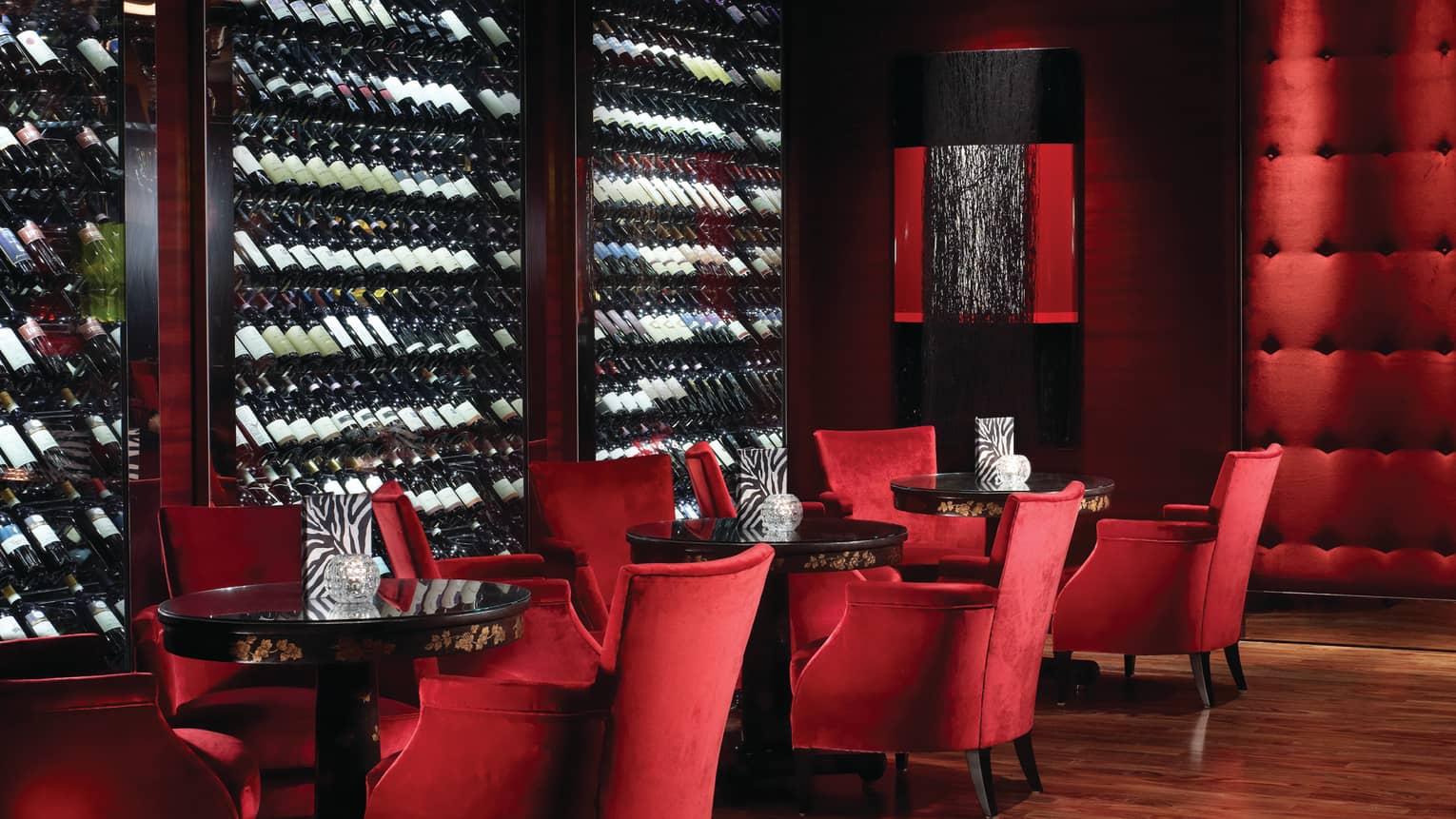 Amaranto Bar red velvet lounge chairs by large glass cellars lined with bottles