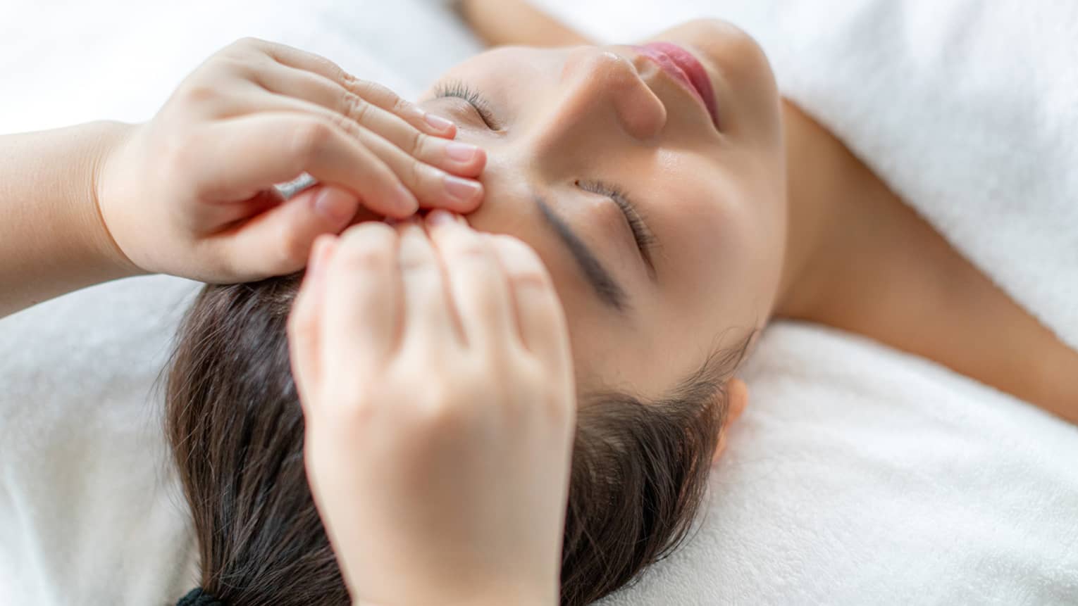 A woman getting a facial massage in a spa.