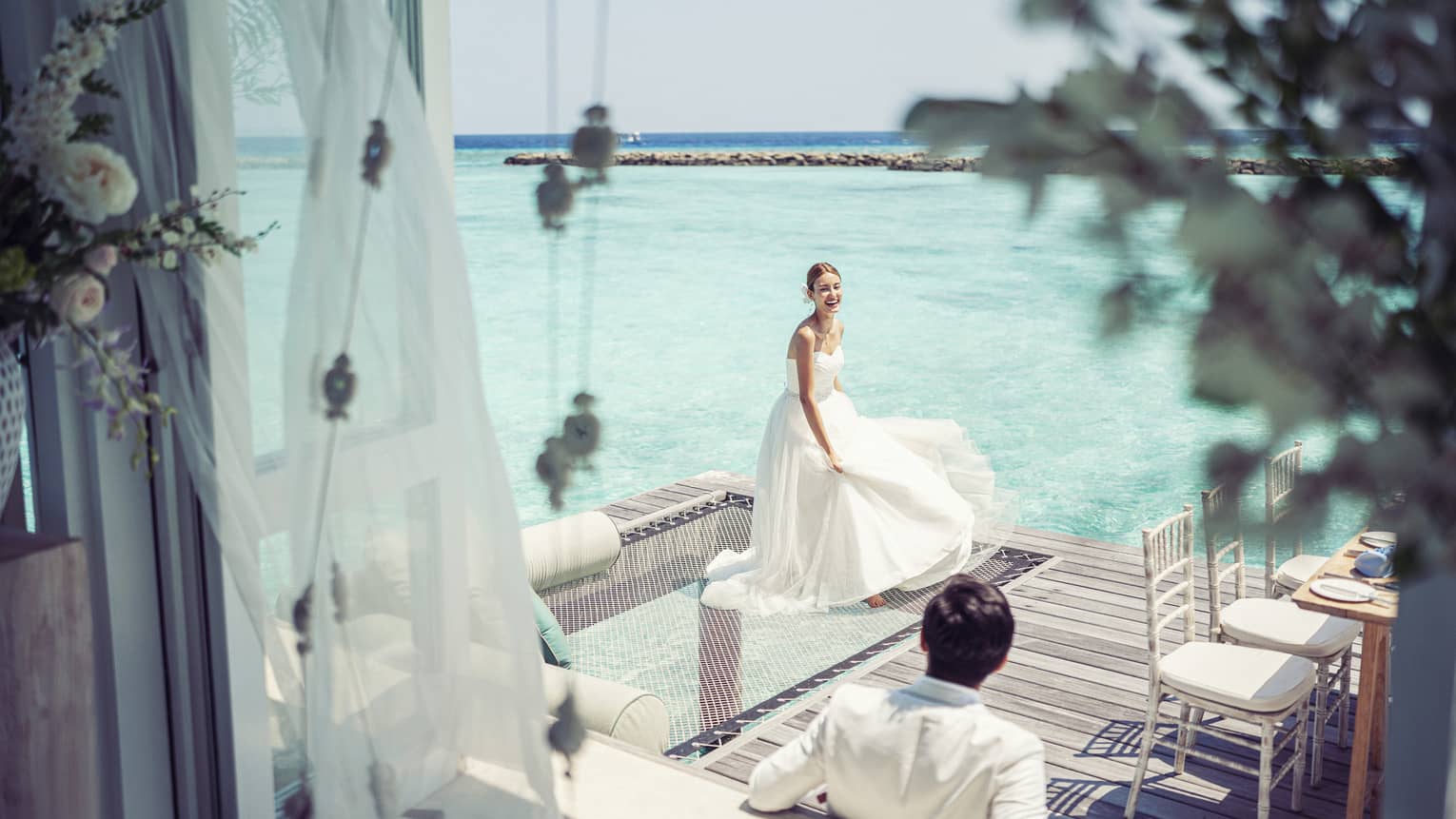 Bride and groom relax before their reception in their overwater wedding bungalow with glass-bottom floor