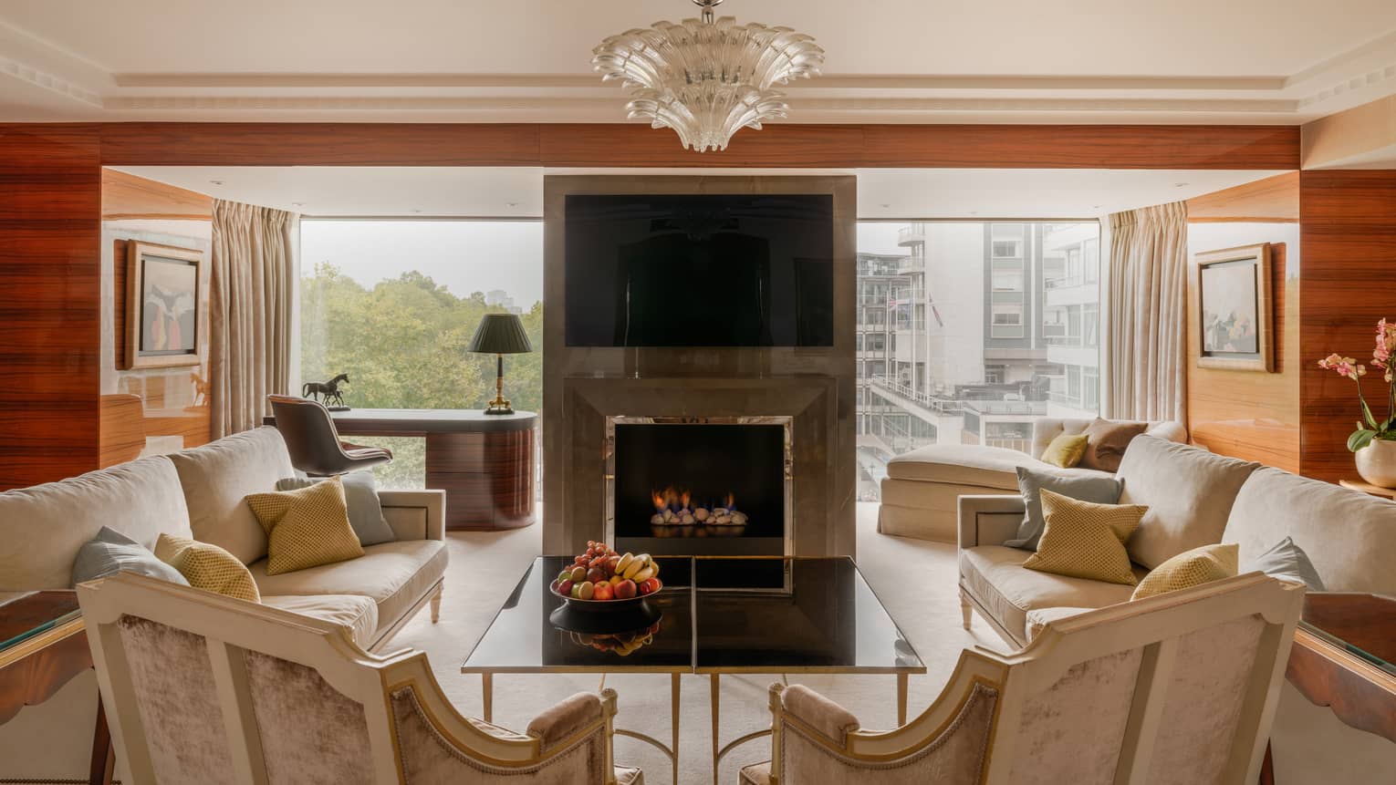Elegant living room of Presidential Suite, with two sofas and two arm chairs, fireplace, TV and chandelier at Four Seasons Hotel London