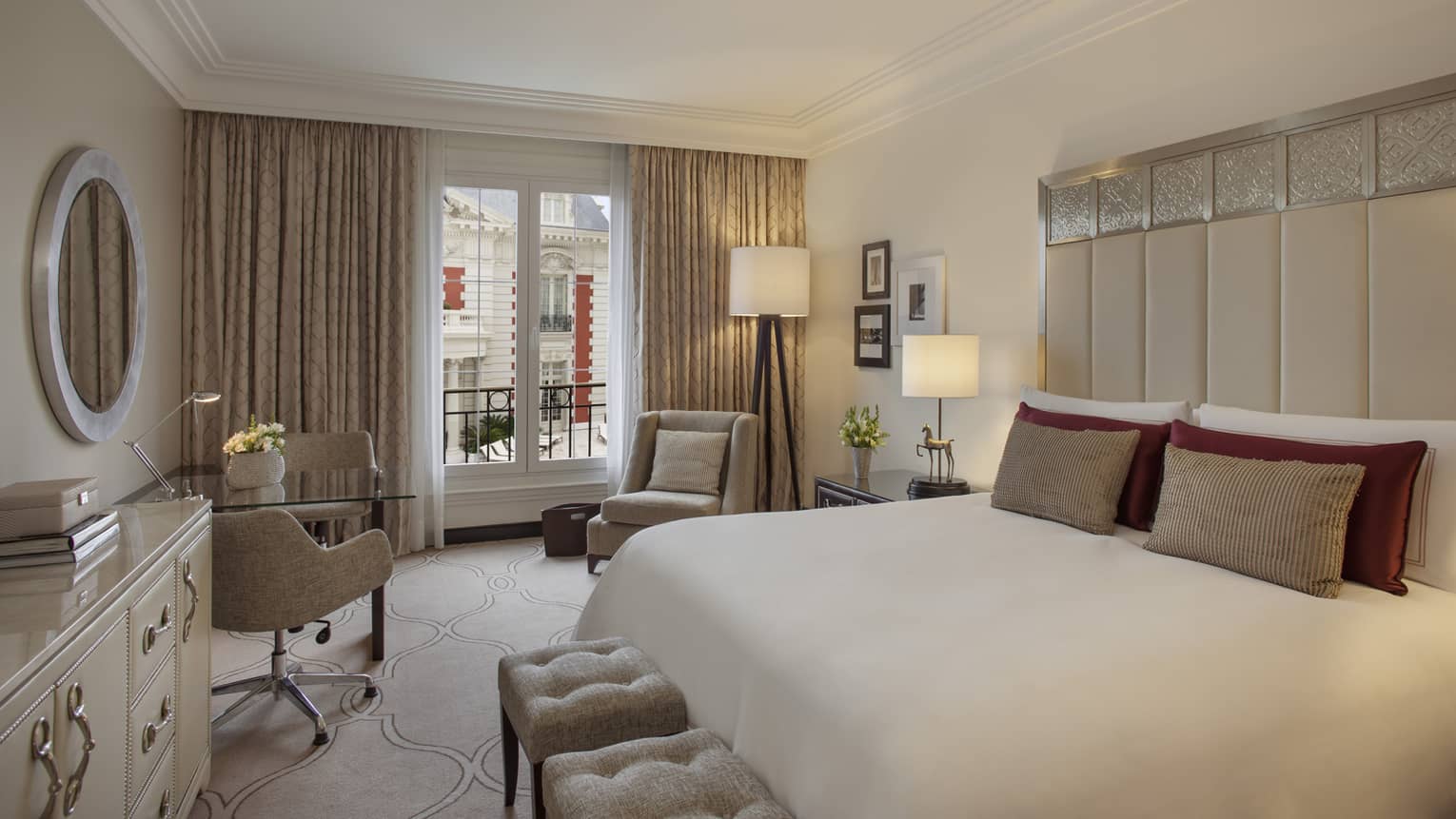 Mansion-View Room with clean, white-and-cream decor, tall padded headboard with silver details, white plush benches, chairs