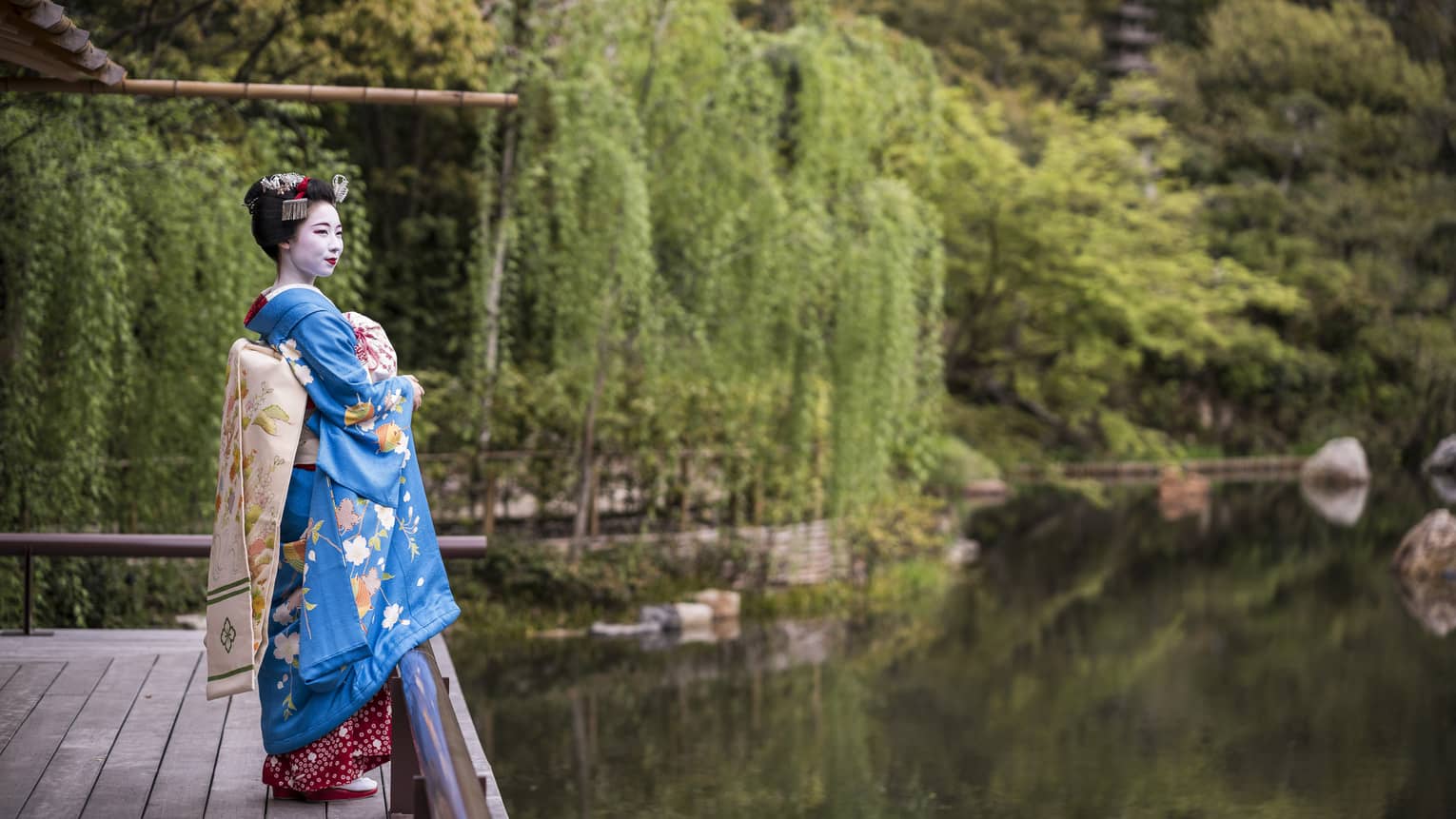A geisha stands on the dock of the yoga barn and overlooks the serene lake