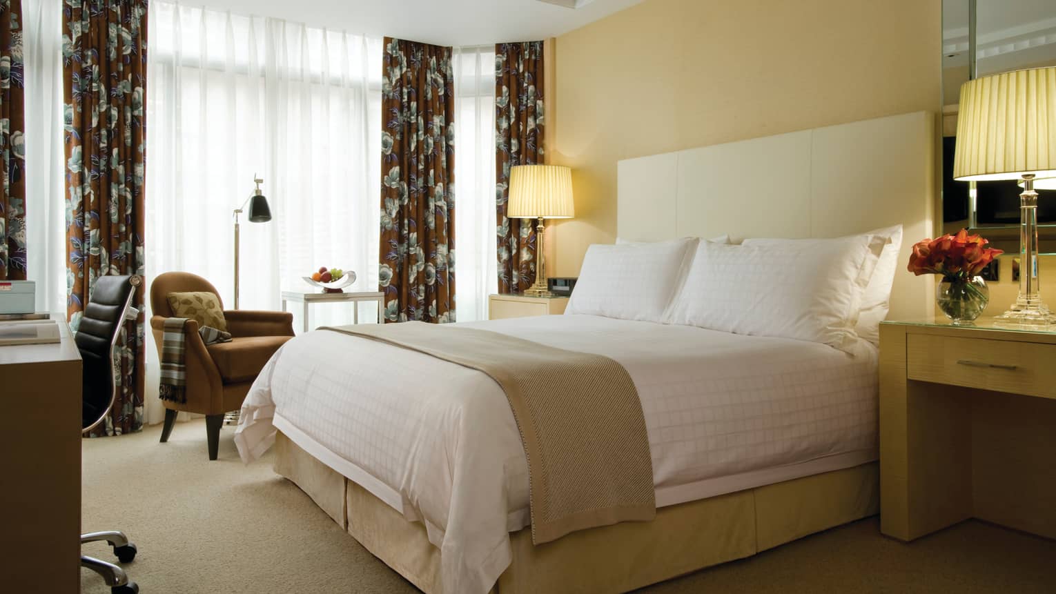 Junior Conservatories guest room, hotel bed with white headboard, armchair by curtains