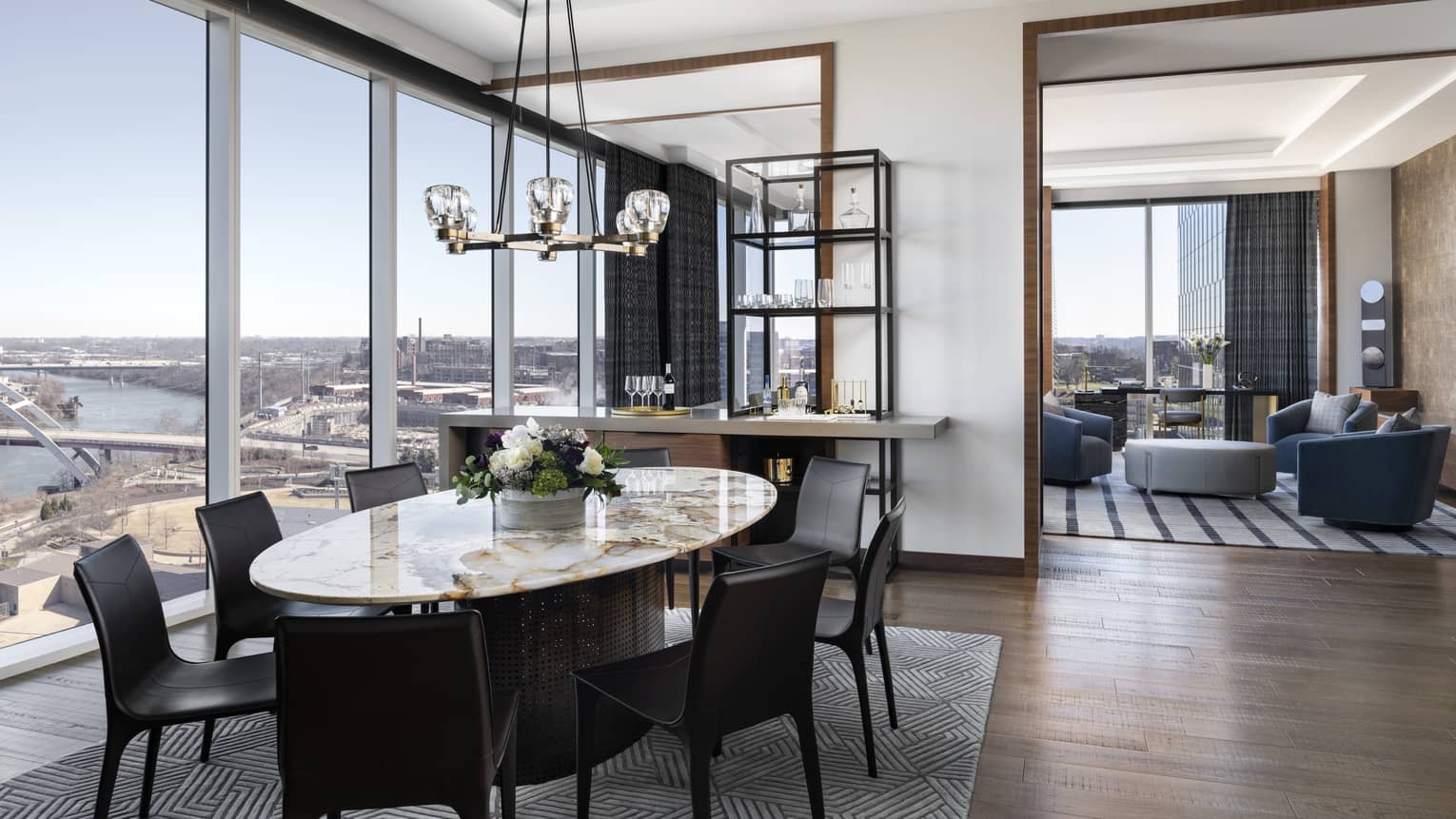Large hotel suite with marble oval-shaped dining table and living room, city view