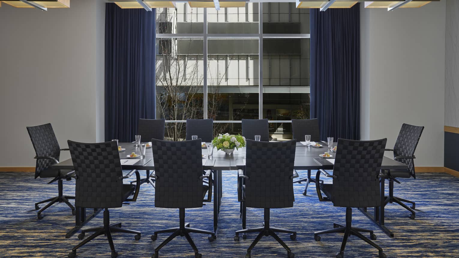 A room with a large table and many black chairs around it.
