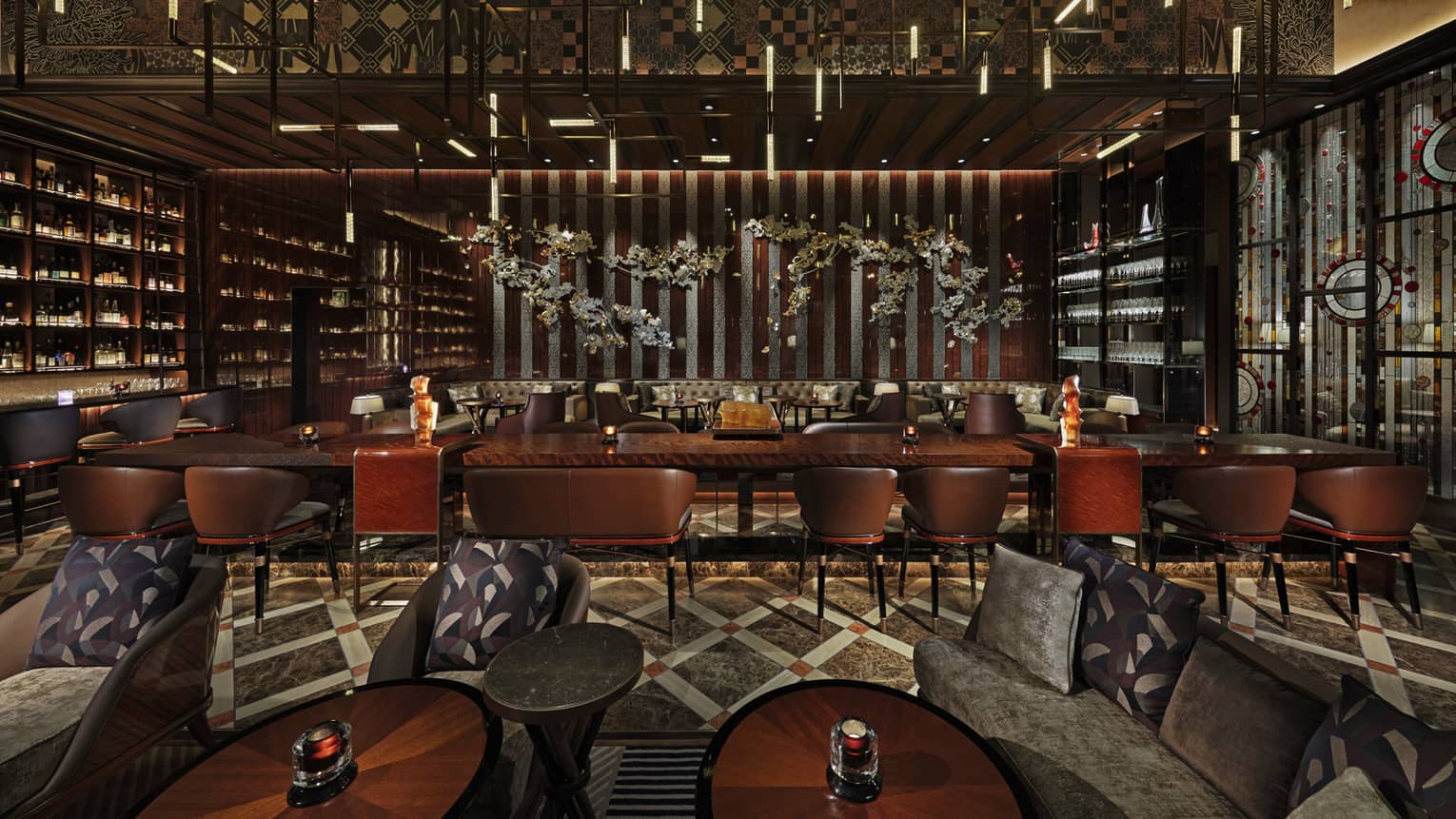 Long rectangular banquet tables with high-backed leather seats, fully-stocked bar wall to the left, lowlighting, wood decor