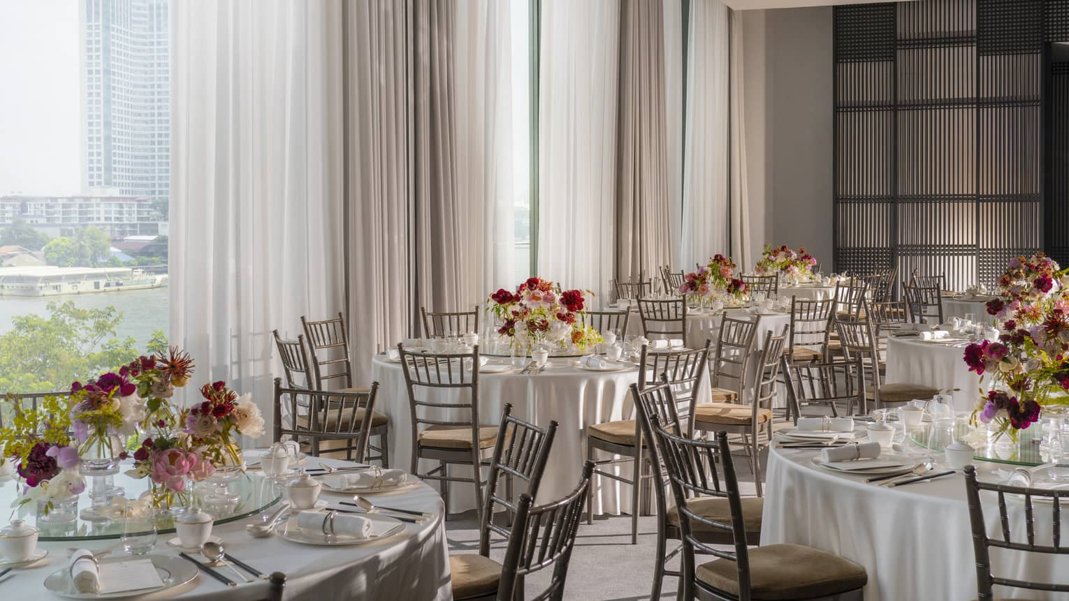 Ballroom with banquet rounds and floral centrepieces, floor-to-ceiling windows with views of downtown