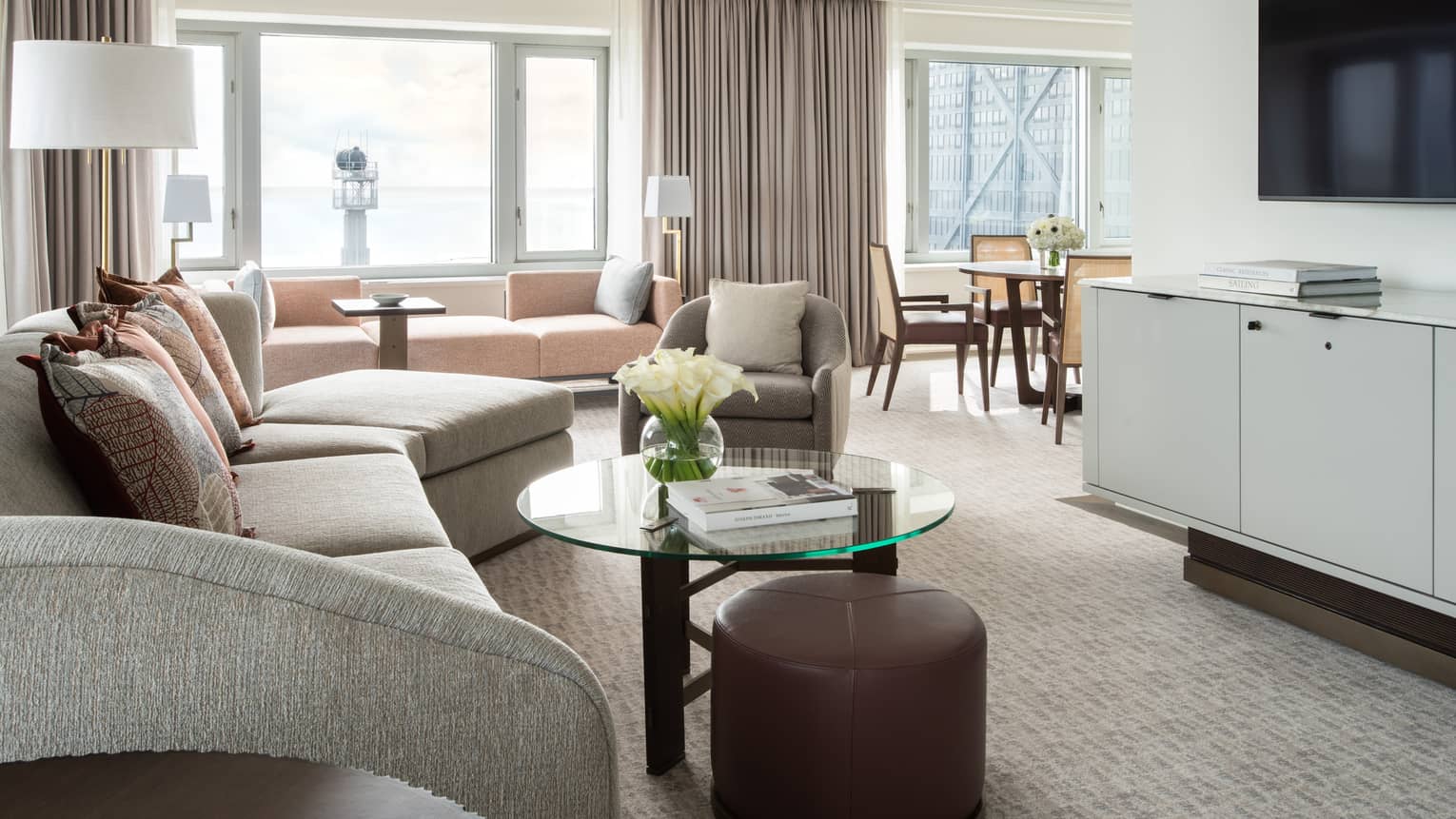 Living room with curved sofa, glass coffee table, TV, carpeting, opening to the dining area