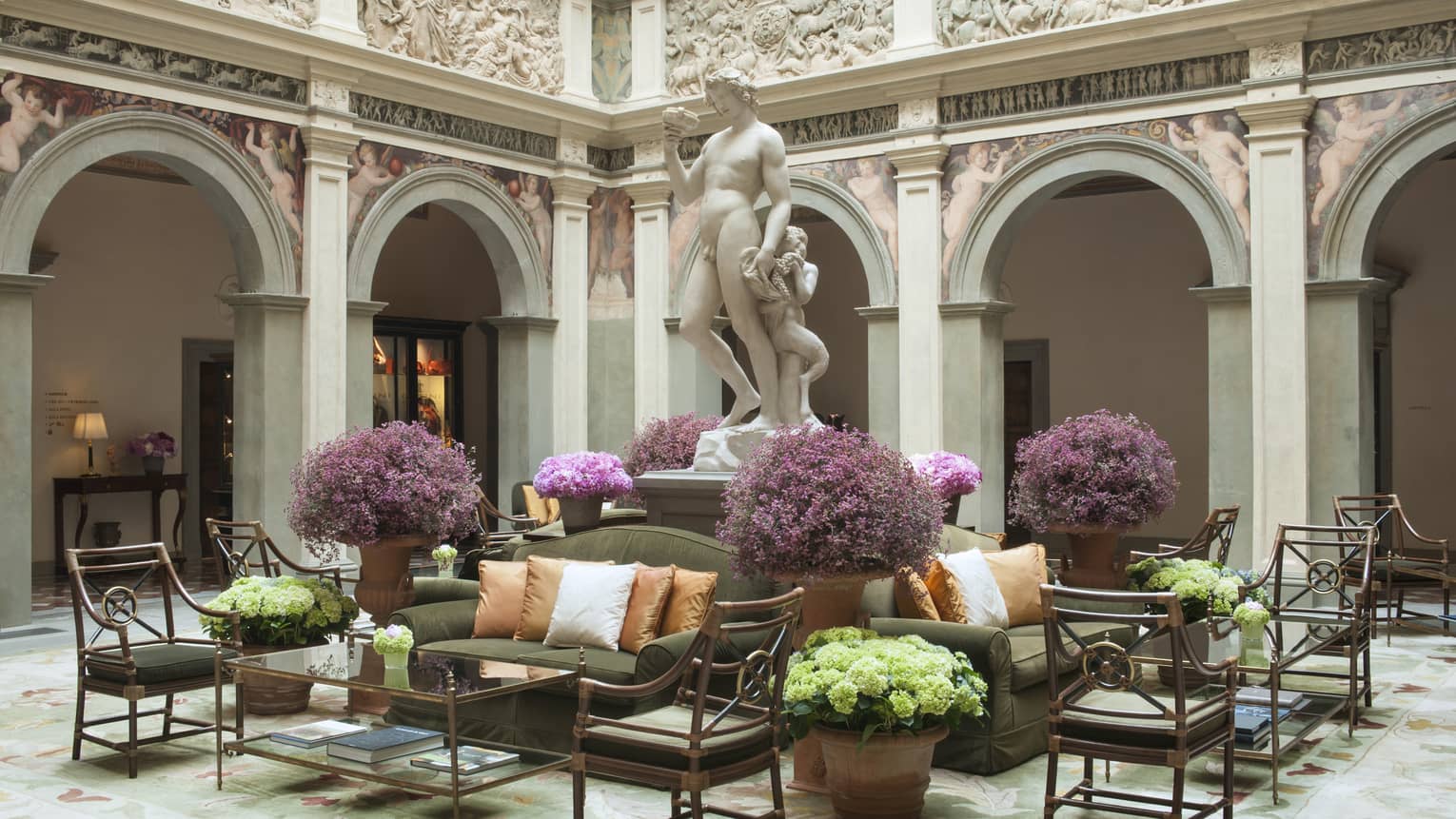 Il Palazzo lobby, sunny atrium with stone statue on pedestal over seating area, purple flowers