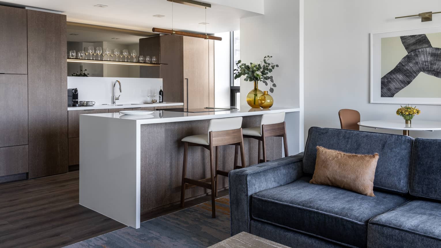 Kitchen area with white island, two chairs, wooden cabinets