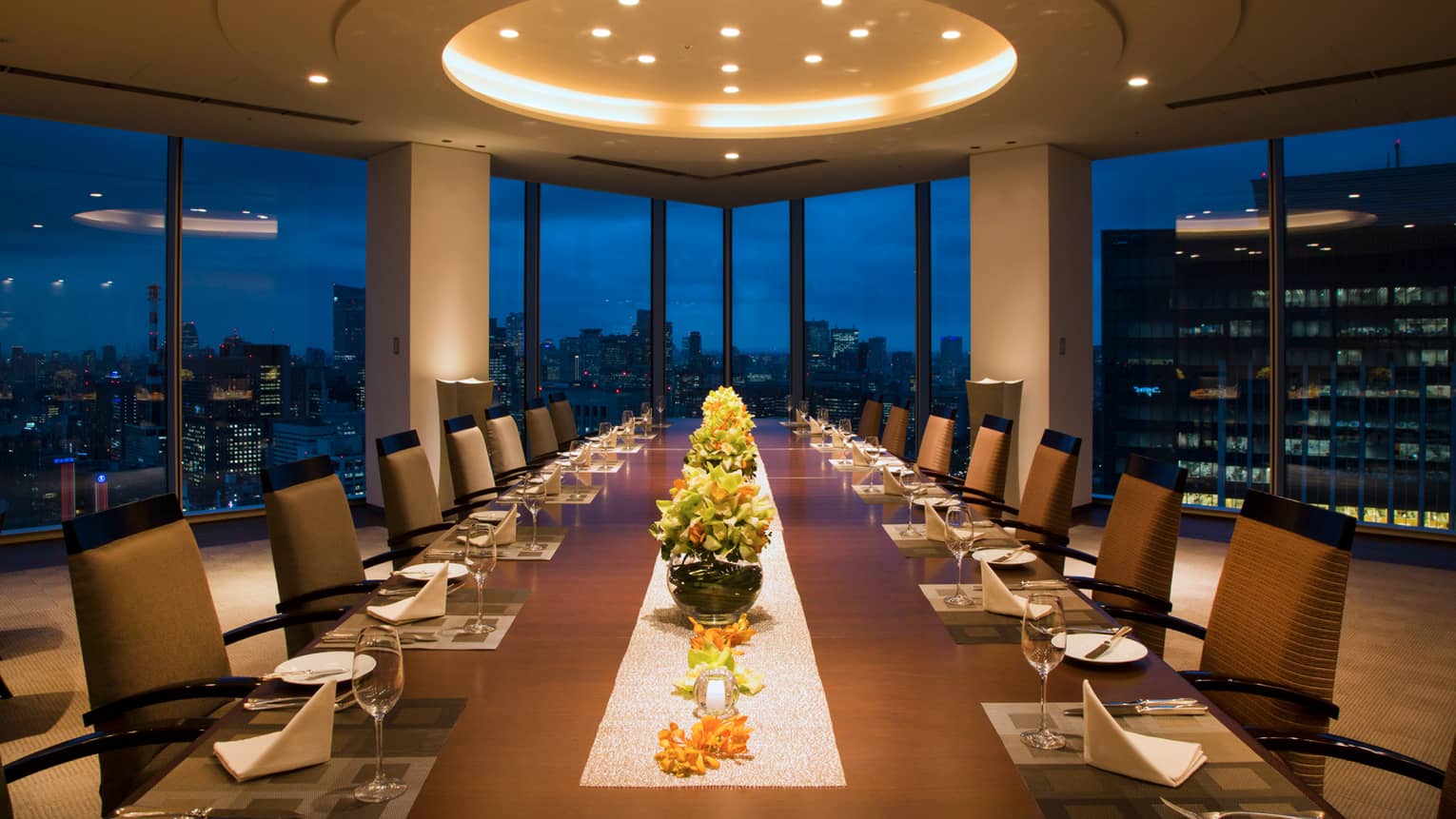Long Executive Dining Room table under dome ceiling with lights, city lights through window