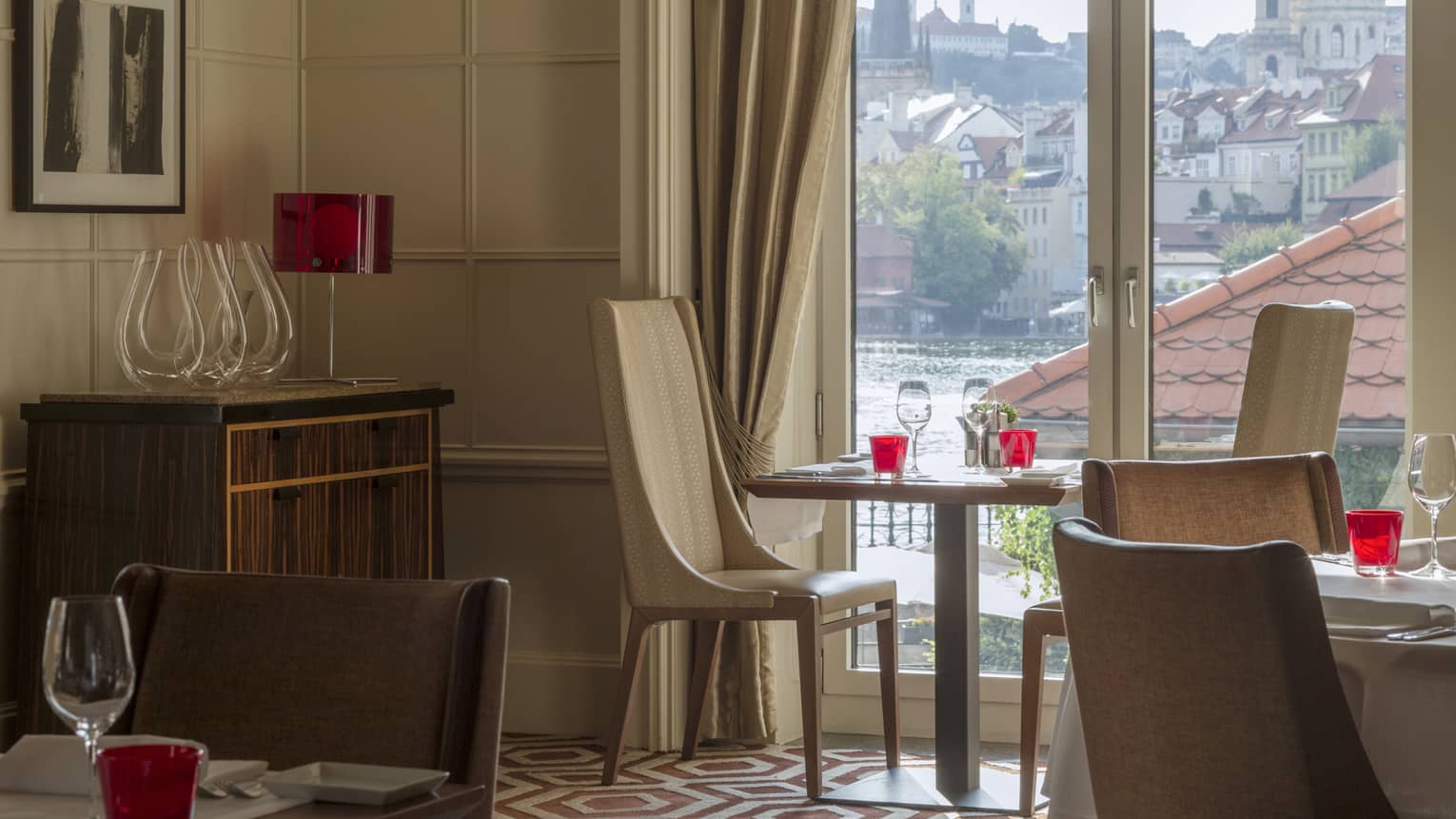 The inside of a restaurant with a view of water and an old city.