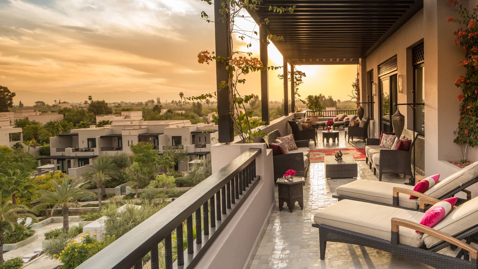 Moorish gardens below below long white hotel balcony with plush patio furniture 