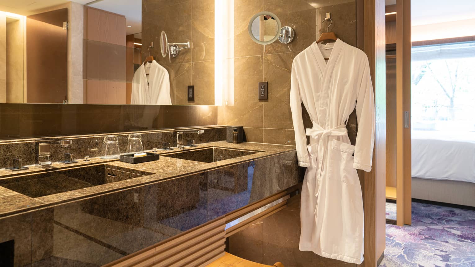 Luxury bathroom with a double-sink vanity, large mirror and a plush white robe hanging beside the counter
