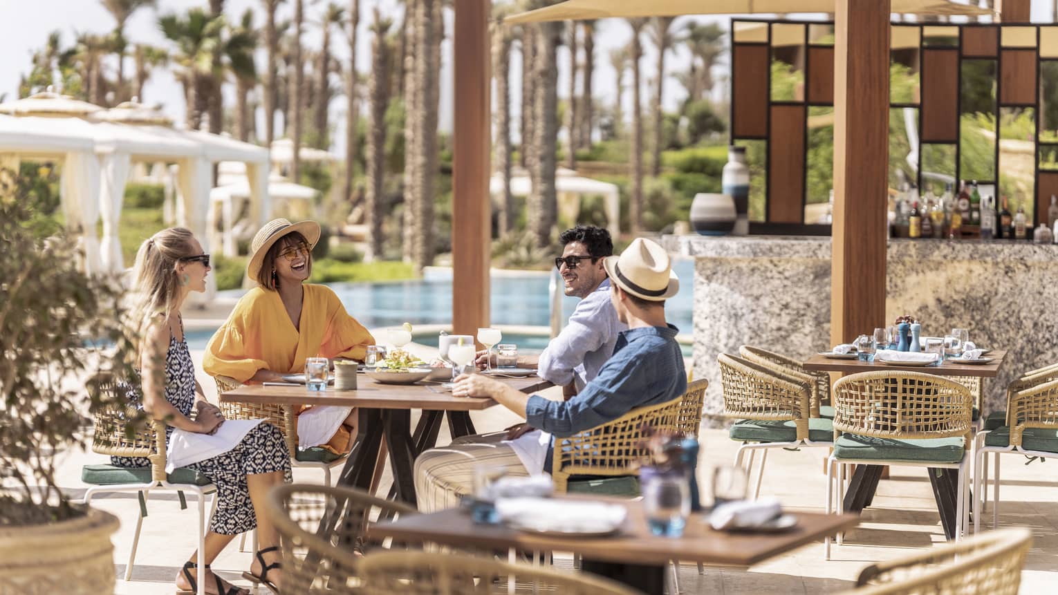 Friends enjoying lunch outdoors by the pool in luxury hotel