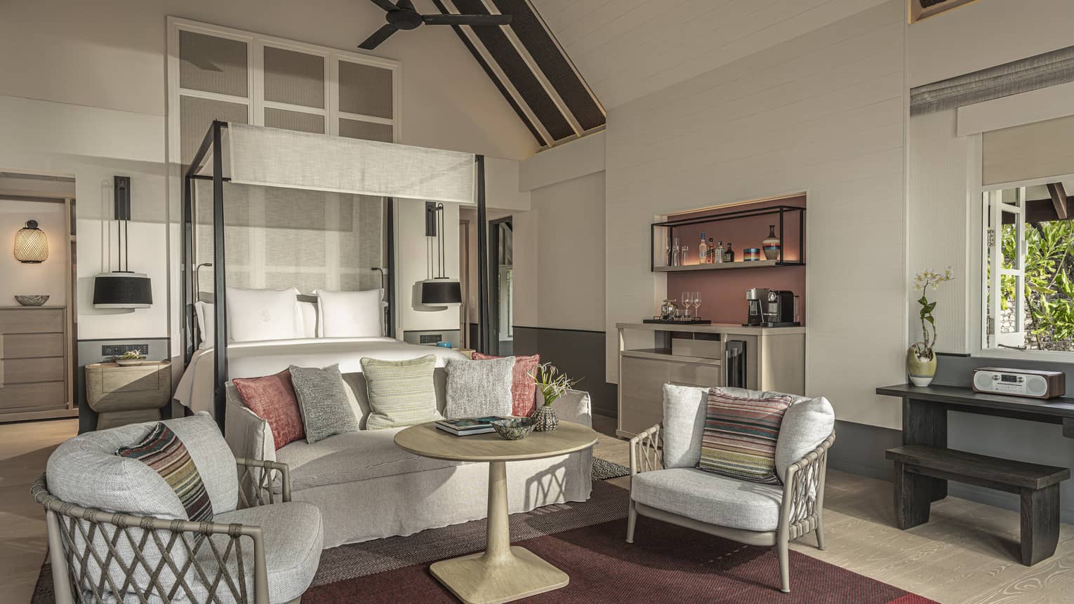 Master bedroom with canopy bed, sofa and two chairs, with vaulted beamed ceiling