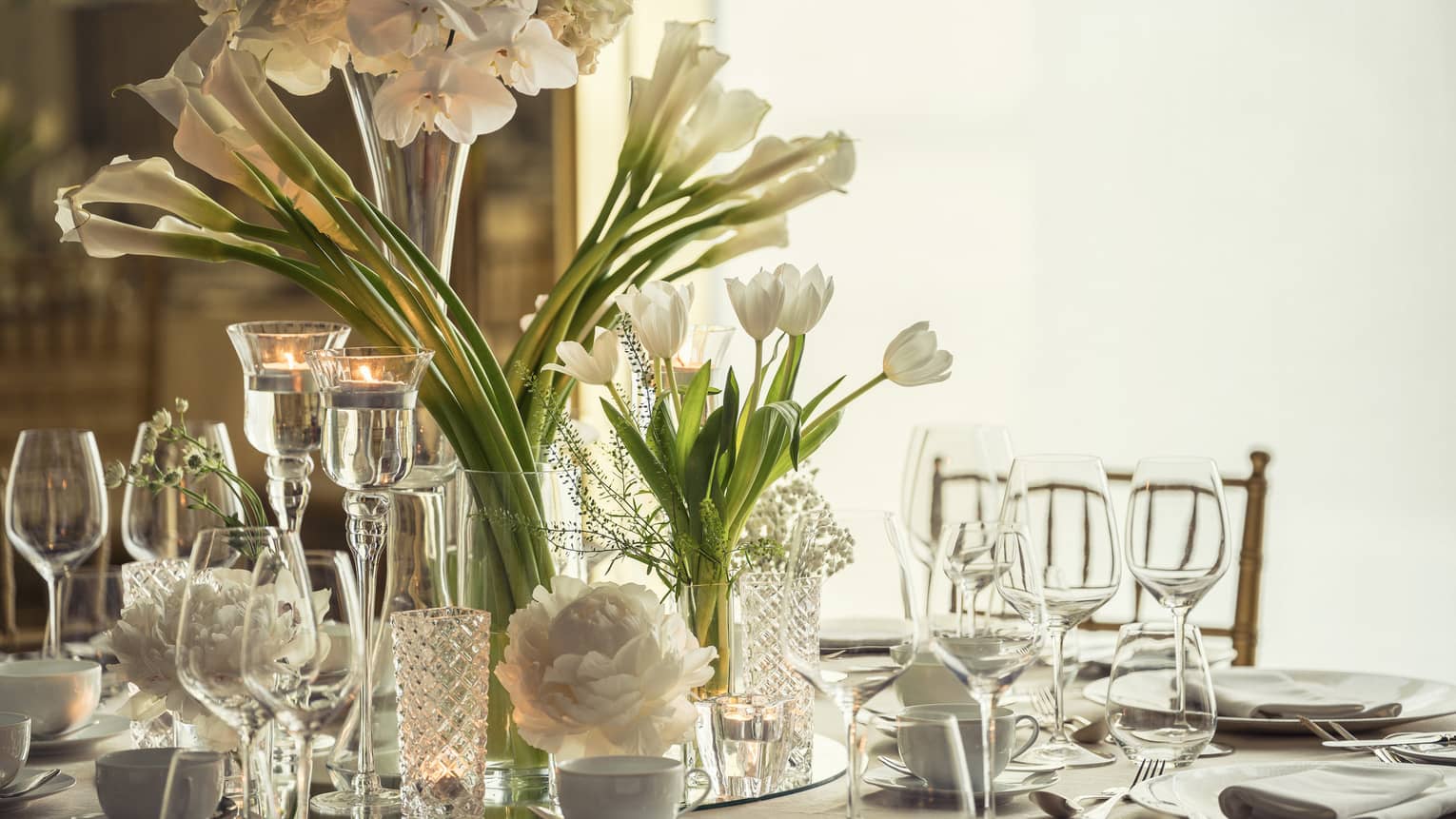 Western Banquet room dining table with glassware, long stemmed white flowers in vase